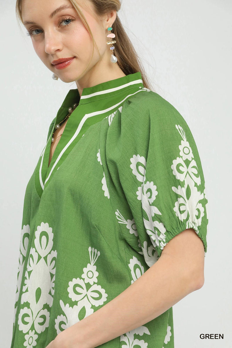 Woman wearing a green dress with white floral patterns on a plain background