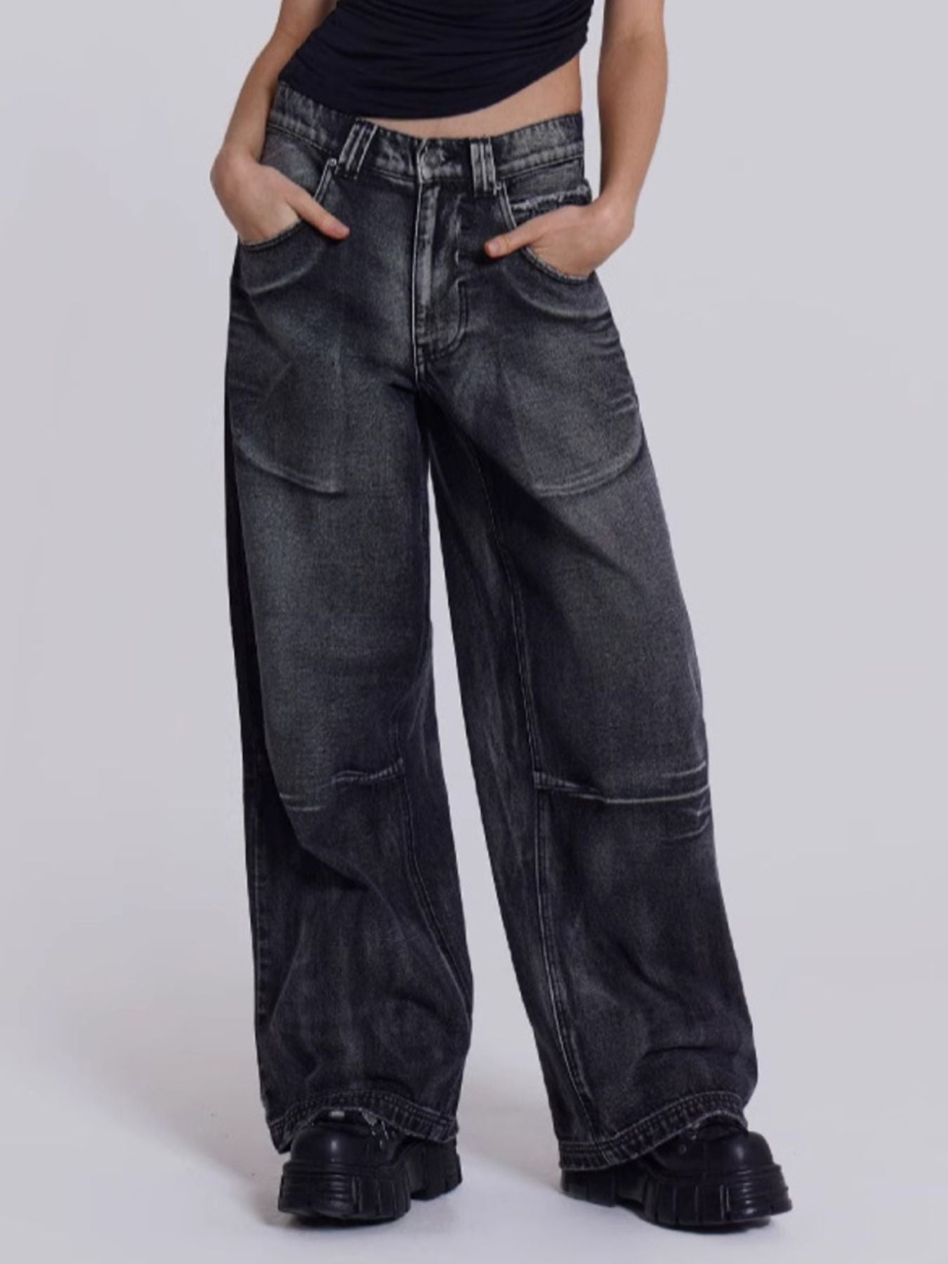 Person wearing wide-leg black jeans on a plain background