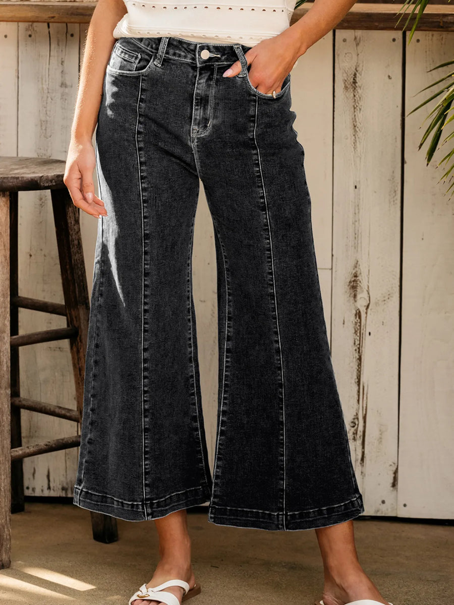 Person wearing black wide-leg jeans in a casual setting.