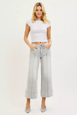 Woman wearing a white crop top and light gray wide-leg pants on a white background