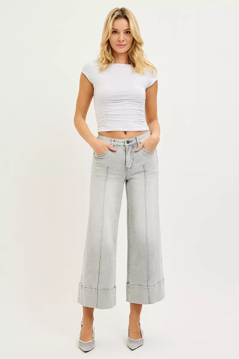 Woman wearing a white crop top and light gray wide-leg pants on a white background