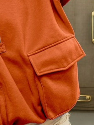 Close-up of an orange jacket with a pocket against a neutral background