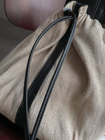 Close-up of a beige drawstring bag with a black cord.