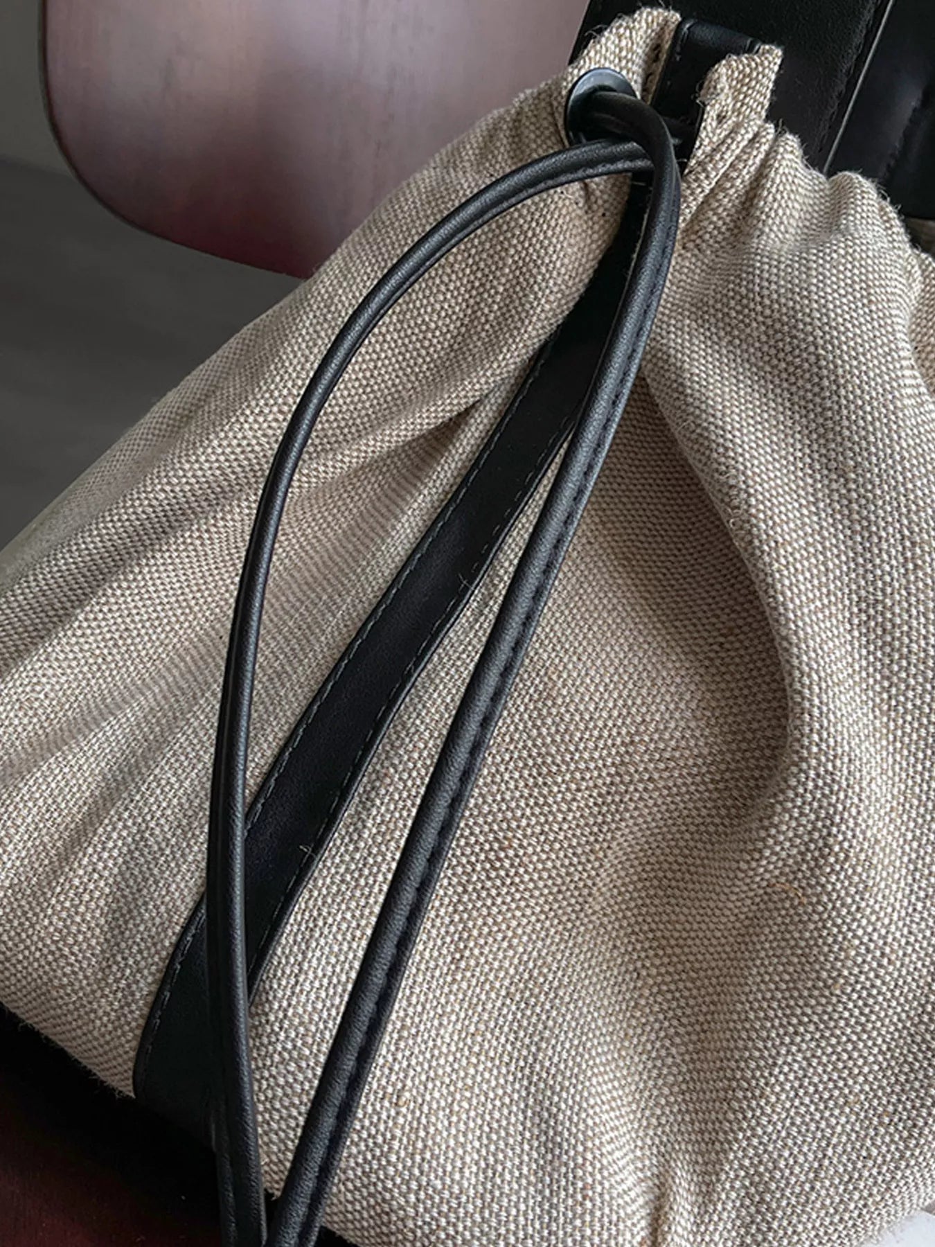 Close-up of a beige drawstring bag with a black cord.