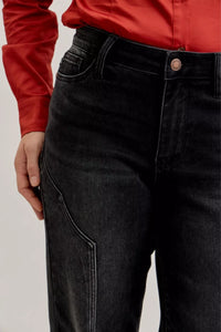 Person wearing black jeans with a red shirt on a light gray background
