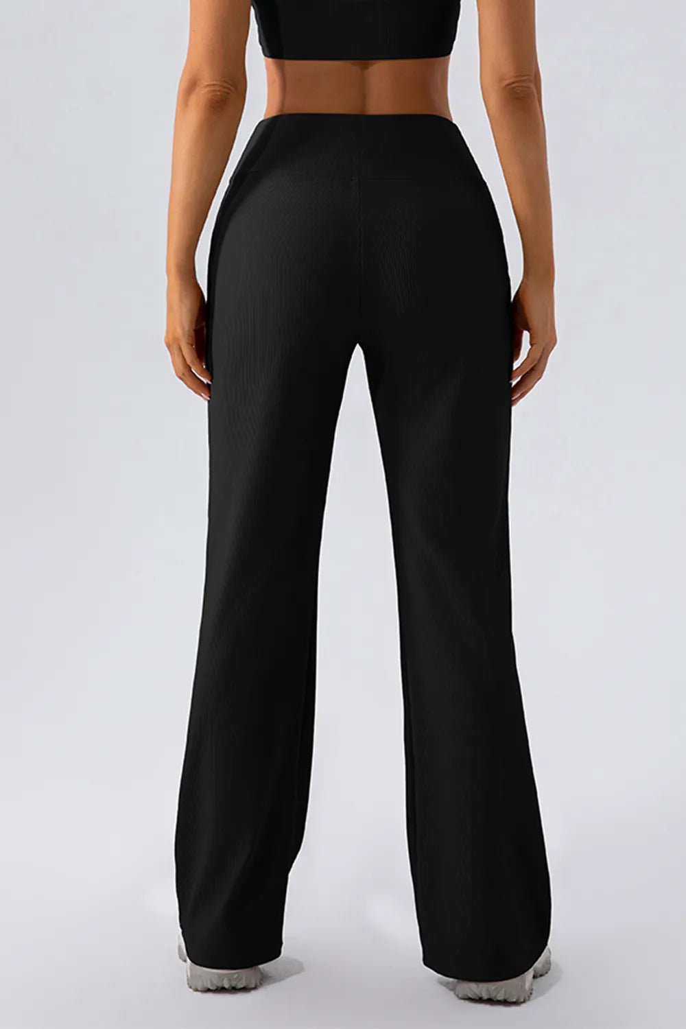 Person wearing black high-waisted pants on a white background