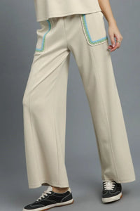 Beige pants with blue accents worn by a person on a gray background