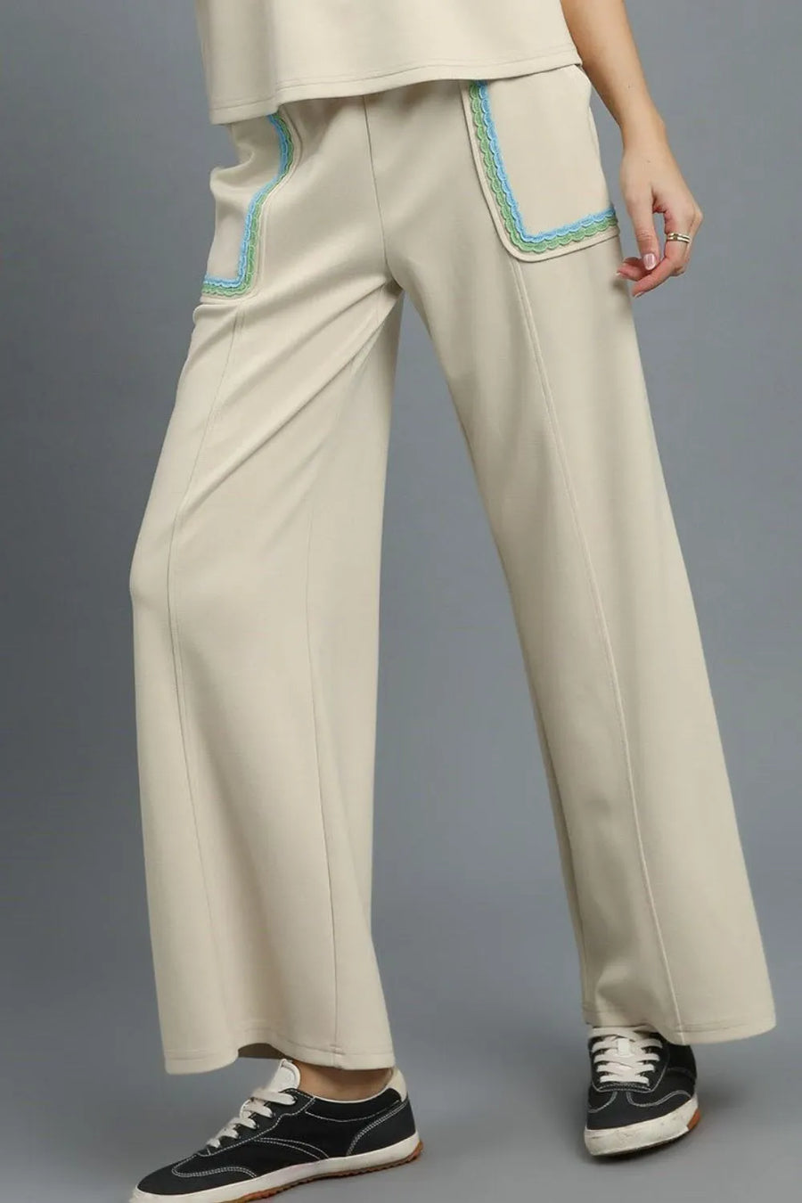 Beige pants with blue accents worn by a person on a gray background