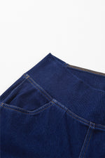Close-up of a blue denim fabric with stitching details on a white background