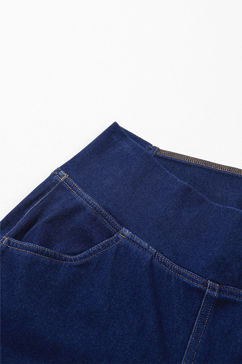 Close-up of a blue denim fabric with stitching details on a white background