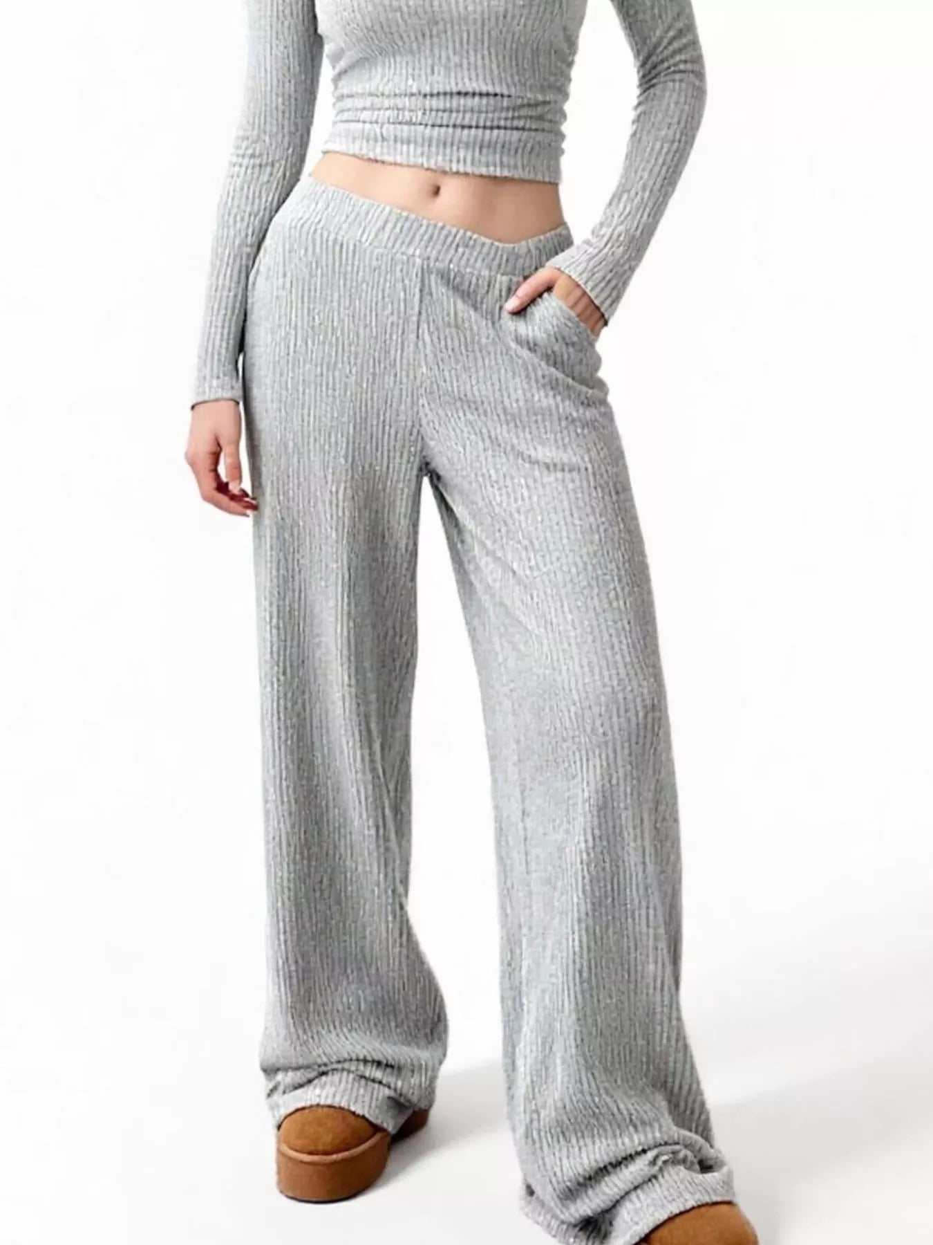 Person wearing gray ribbed knit pants and a cropped sweater on a white background