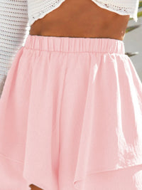 Pink skirt with brown top worn by a person, blurred background