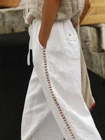 White pants with decorative stitching detail on a blurred background