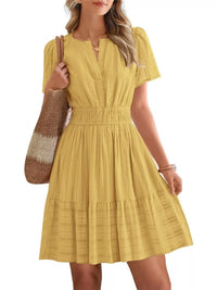Woman wearing a yellow dress holding a brown and beige striped bag on a white background