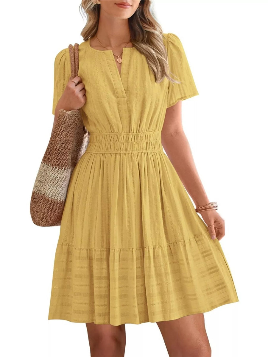 Woman wearing a yellow dress holding a brown and beige striped bag on a white background