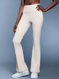 Person wearing white flared pants on a gray background