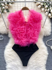 Pink ruffled top and black high-waisted bottom set on a white fur surface with decorative background.