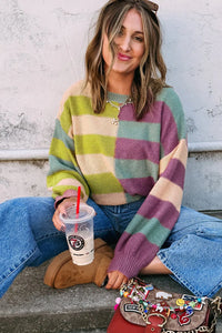 Woman wearing a colorful striped sweater sitting on steps with a drink and small bag.