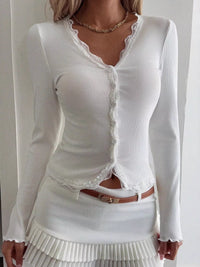 White long-sleeve top with lace details worn by a person on a plain background