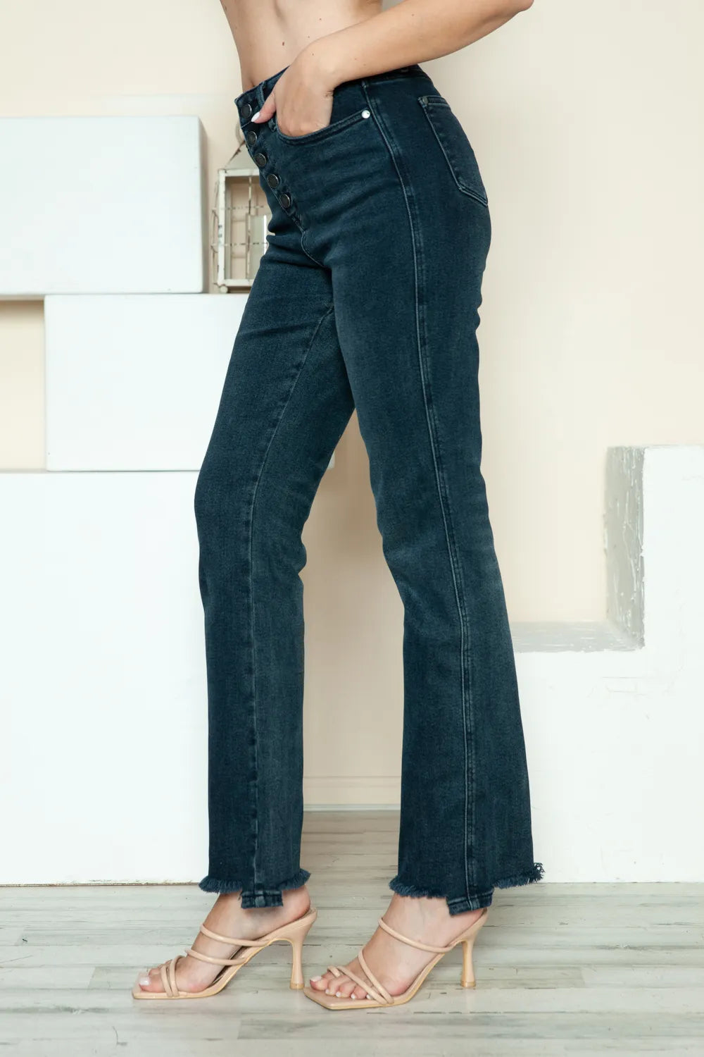 Person wearing dark blue jeans with a neutral background