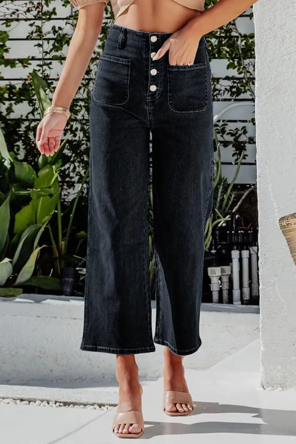 Person wearing black wide-leg jeans with a blurred background