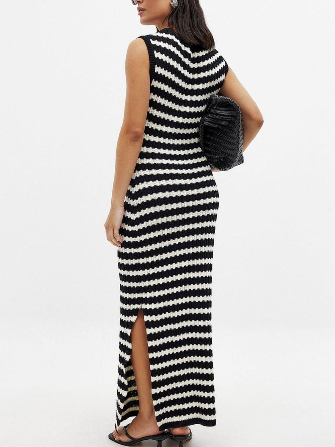 Woman wearing a black and white striped dress with a slit on a white background