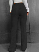 Person wearing dark ribbed wide-leg pants against a gray background