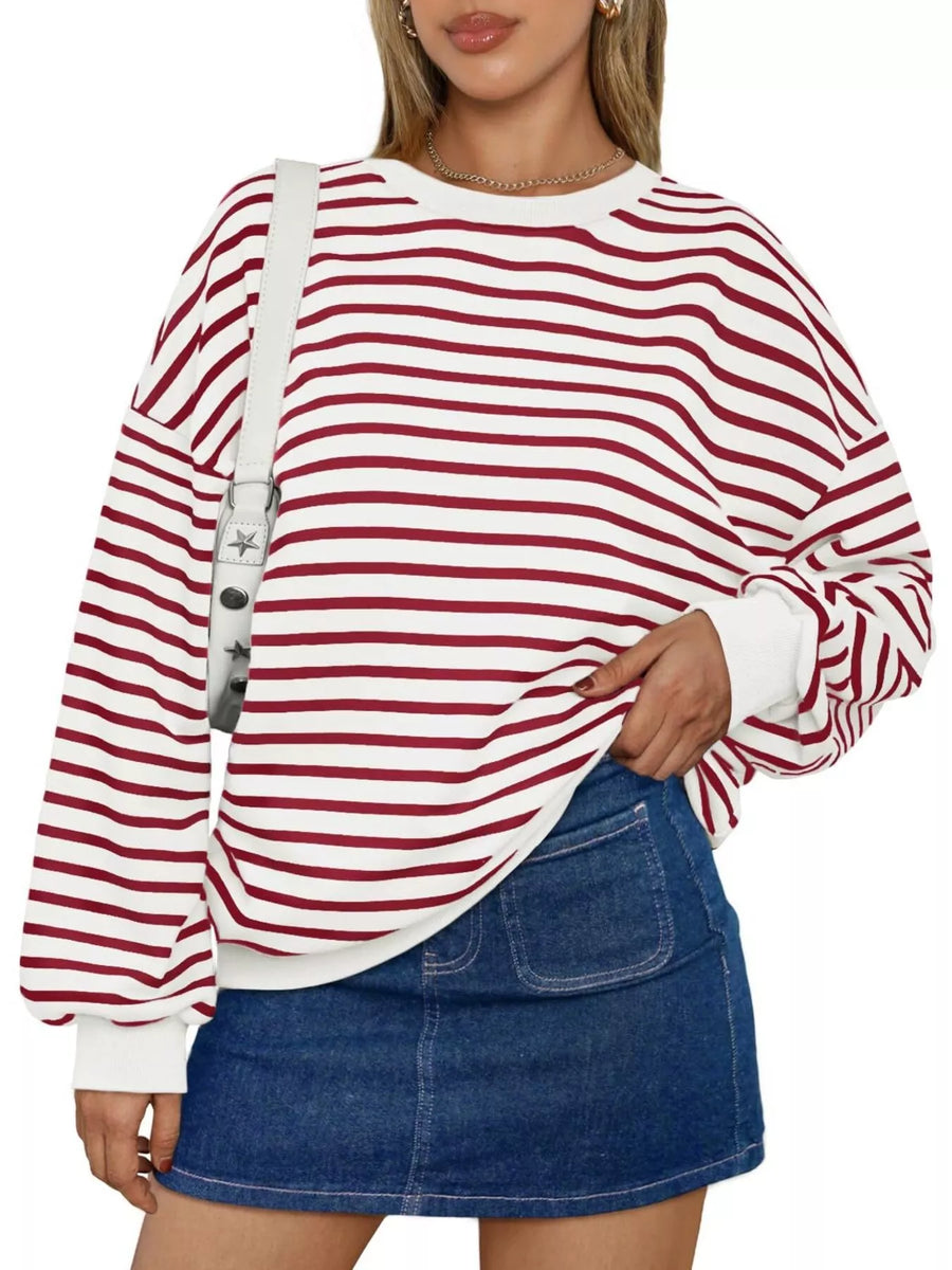 Person wearing a red and white striped sweater with a denim skirt on a white background
