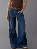 Person wearing blue jeans and a brown shirt on a gray background
