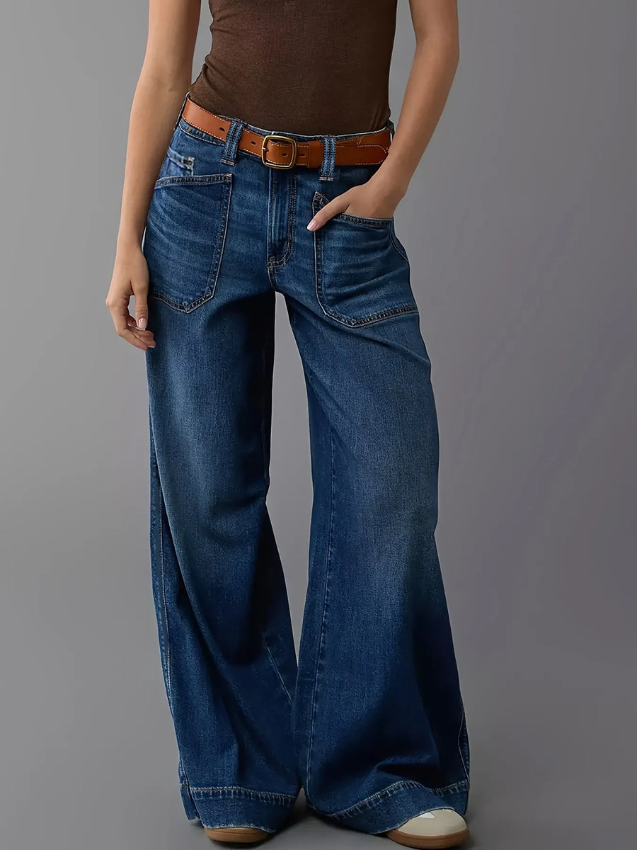 Person wearing blue jeans and a brown shirt on a gray background