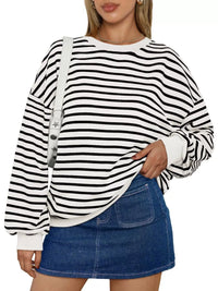 Person wearing a black and white striped sweater with a denim skirt on a white background