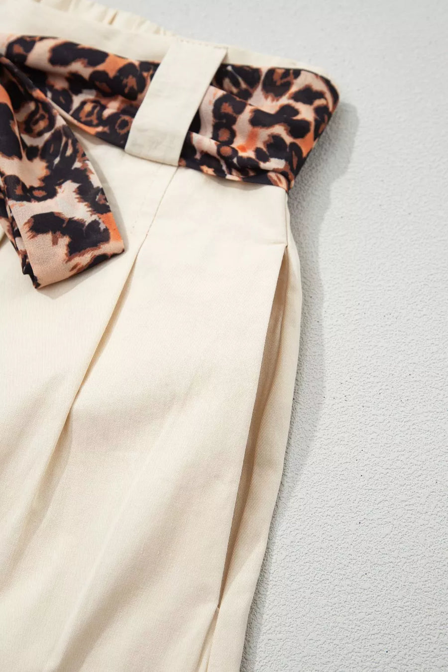 Close-up of a white garment with leopard print trim on a light gray background