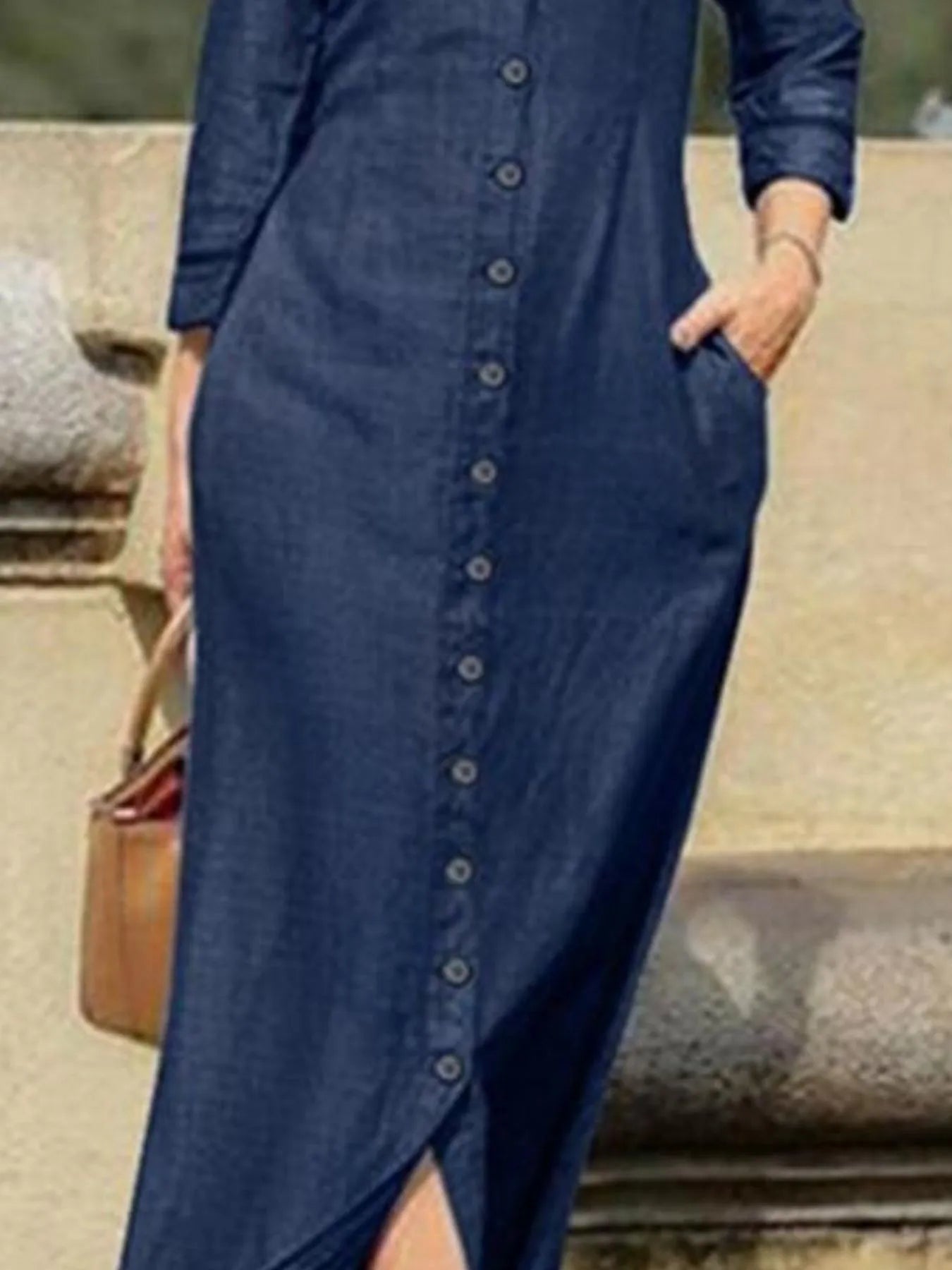 Person wearing a long blue denim dress with a blurred background