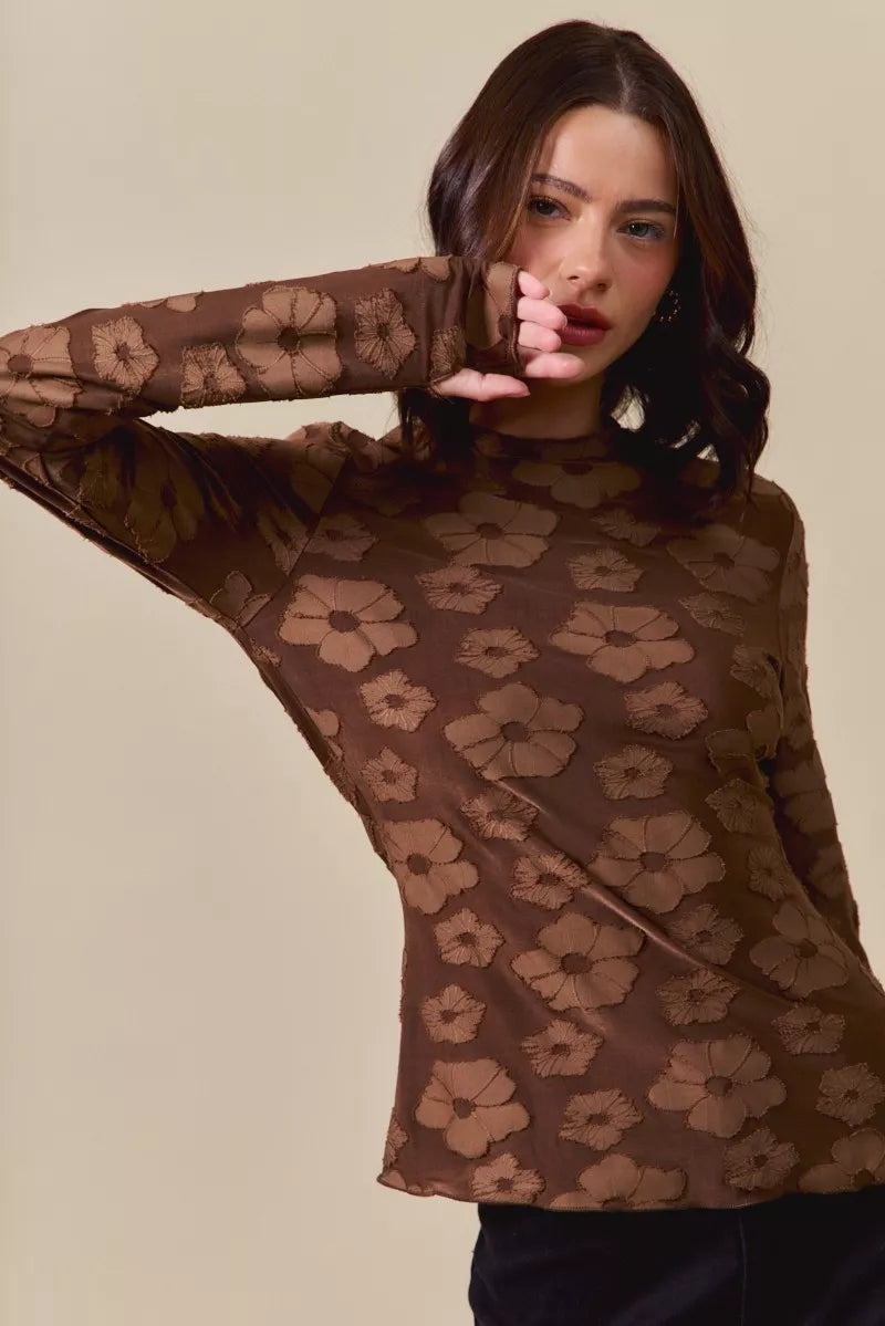 Woman wearing a brown floral patterned top against a beige background