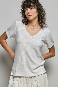 Woman wearing a white textured top against a plain background
