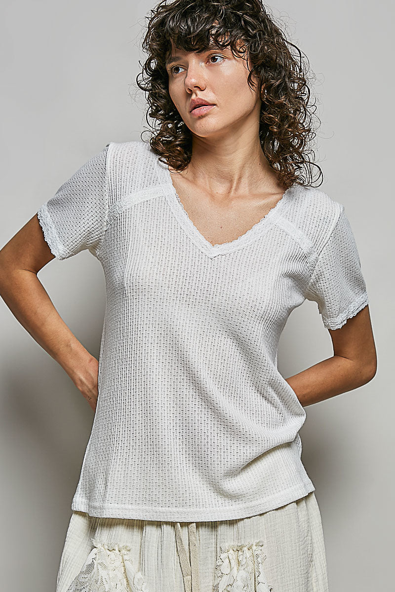 Woman wearing a white textured top against a plain background