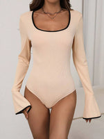 Beige bodysuit with long sleeves and black trim on a neutral background