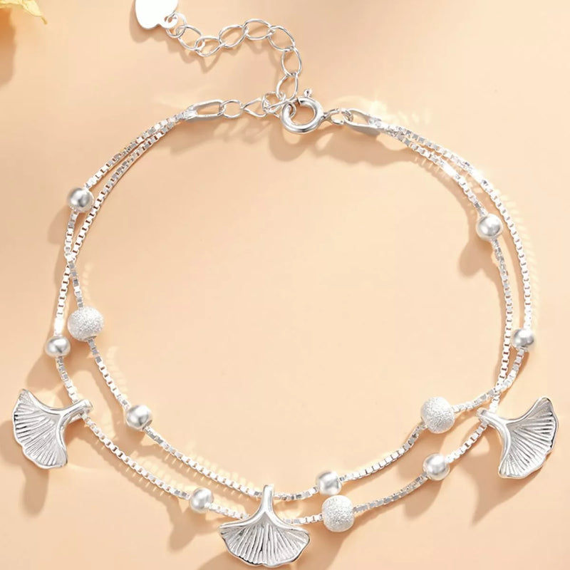 Silver bracelet with leaf and bead designs on a beige background