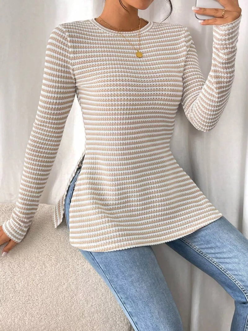 Person wearing a textured long-sleeve top and blue jeans against a neutral background