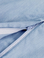 Close-up of a zipper on a light blue denim fabric