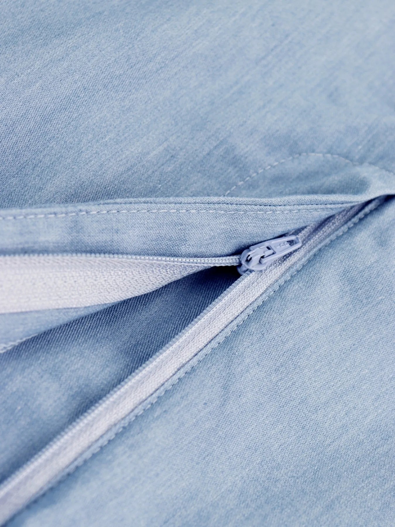 Close-up of a zipper on a light blue denim fabric