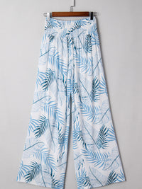 White pants with blue leaf pattern hanging on a gray background