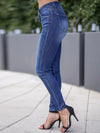 Person wearing blue jeans and black high-heeled shoes on a sidewalk.