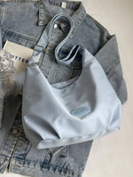 Light blue handbag on a denim jacket with a glass of water and a book in the background.