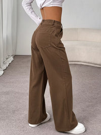 Person wearing brown wide-leg pants in a minimal indoor setting