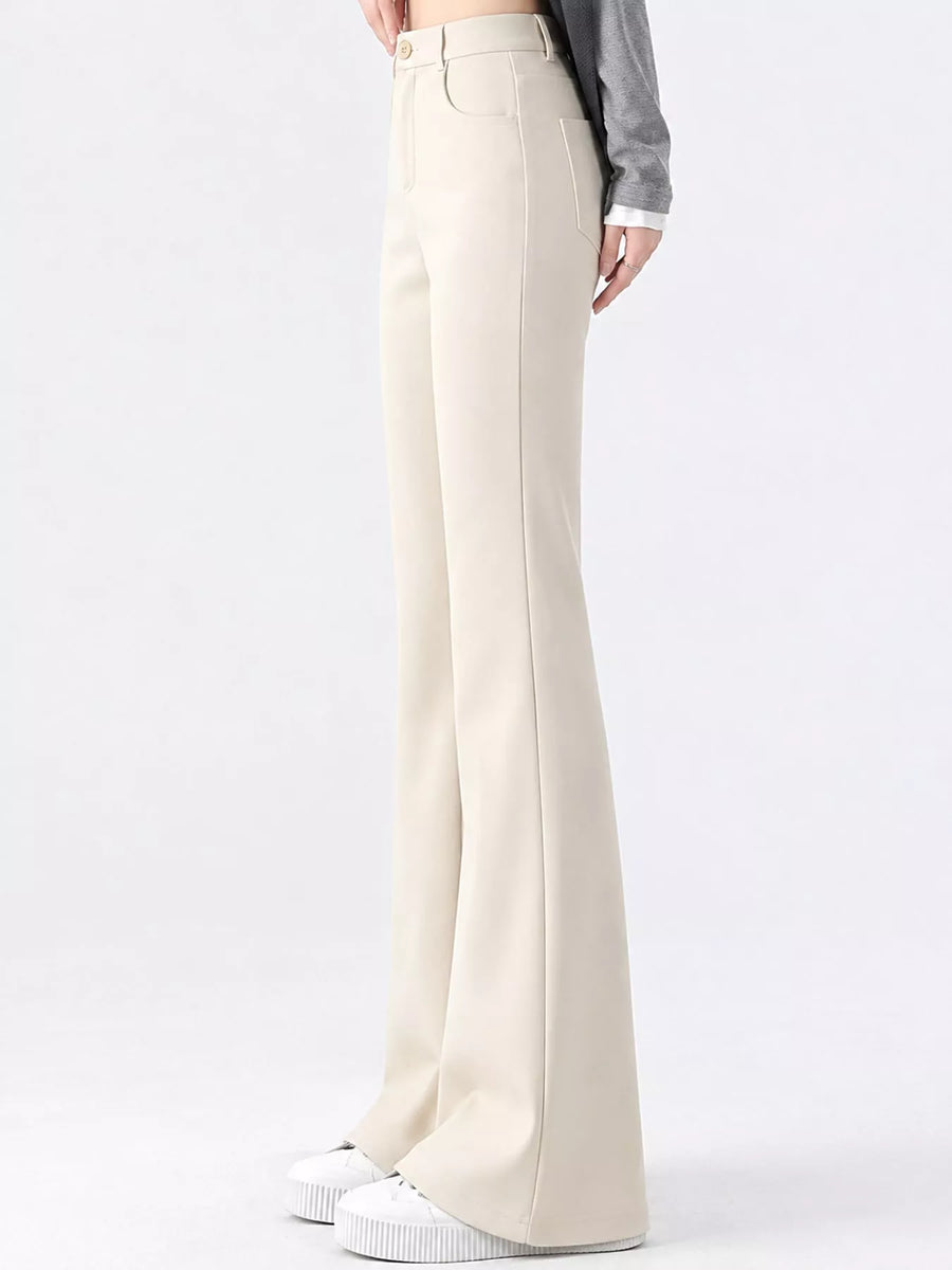 A model is shown from the waist down wearing high-waisted, wide-leg cream pants, a gray long-sleeve top, and white platform sneakers against a plain white studio background.