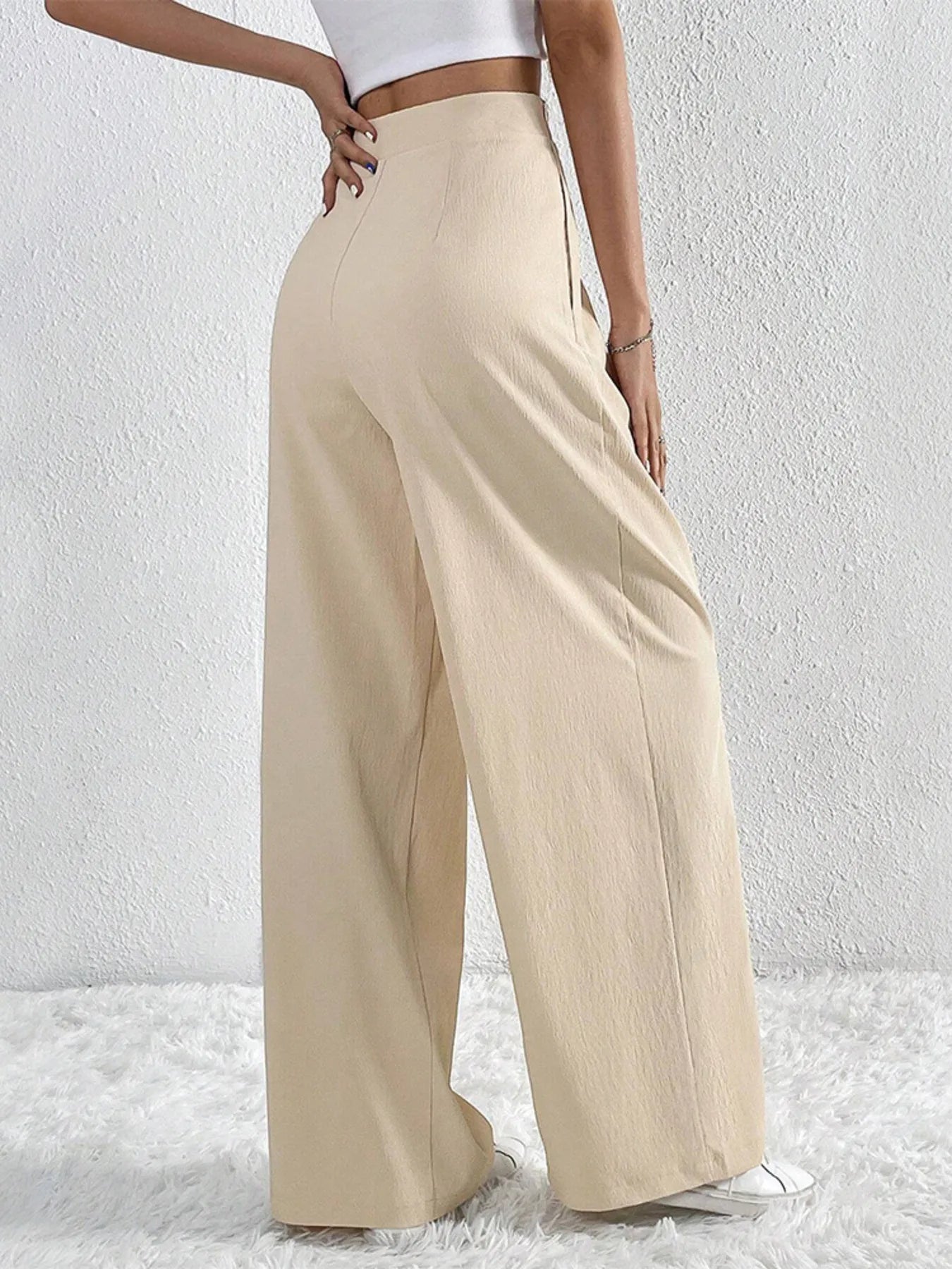 Beige wide-leg pants worn by a person on a white background