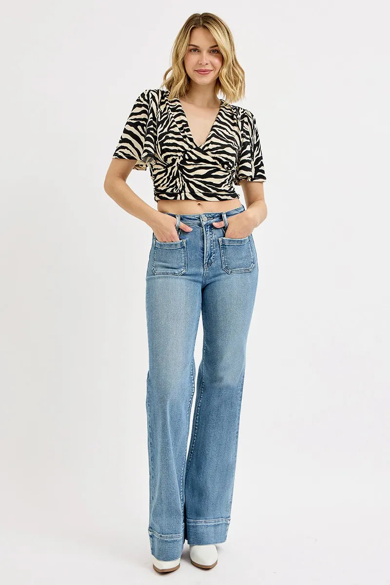 Woman wearing a zebra print top and blue jeans on a white background