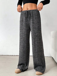Person wearing gray checkered pajama pants on a white background