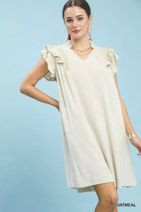 Woman wearing a white dress with ruffled sleeves against a light blue background